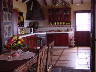 Przytulna wiejska kuchnia z drewnianymi meblami, kwiatową dekoracją i kafelkową podłogą.