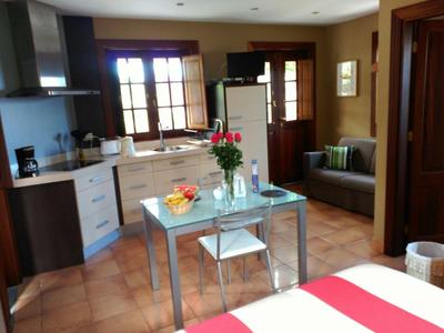 Vue d'une cuisine moderne avec table à manger, chaises et coin salon dans une chambre d'hôtel.