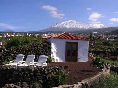 Petit bâtiment blanc avec quatre transats devant un volcan enneigé