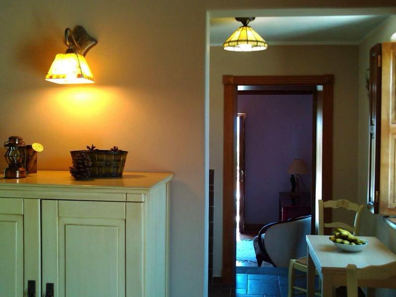 Petit coin repas avec table en bois et chaises, éclairé par des lumières murales et plafonnières chaleureuses.