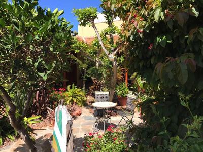 Piccola area giardino con pavimento in pietra, tavolo e sedie circondati da verde rigoglioso.