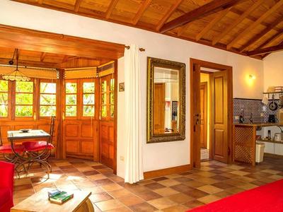 Accogliente zona giorno con soffitto in legno, grandi finestre e piccolo angolo pranzo in una stanza luminosa.