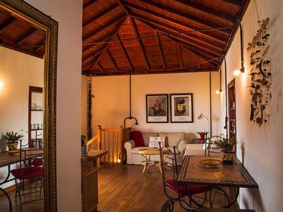 Camera d'hotel accogliente con soffitto a travi di legno, tavolo da pranzo, divano ed elementi decorativi alle pareti.