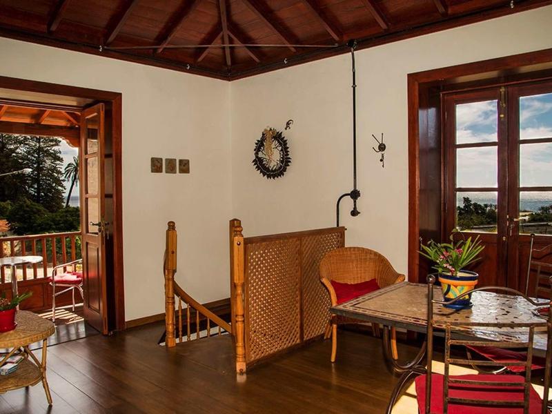 Stanza accogliente con soffitto a travi di legno, zona salotto e porte sul balcone con vista.
