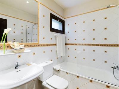 Bagno luminoso con vasca, toilette, lavabo e un grande specchio.