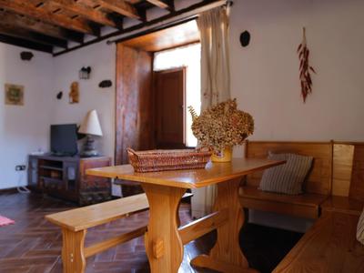 Gemütlicher Landhausraum mit Holzmöbeln, blumenverziertem Tisch und Fenster mit Licht.