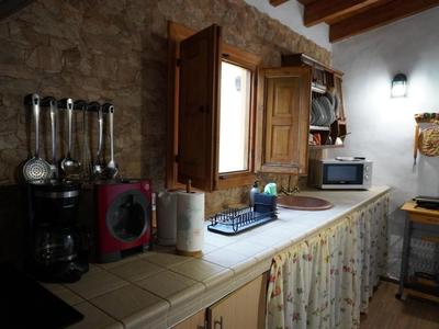 Rustikale Küche mit offenem Fenster, Gewürzen, Mikrowelle und Küchentüchern unter der Arbeitsplatte.