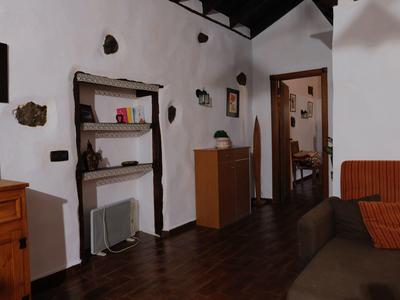 Gemütlicher Raum mit Holzfußboden, weißen Wänden, Regalen, Kommode und braunem Sofa.