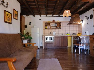 Gemütliche Küche mit Holzboden, brauem Sofa, weißem Essbereich und Holzmöbeln im Landhausstil.