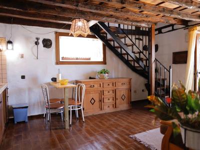 Rustikale Küche mit Holzbalkendecke, Holzboden, Metalltreppe und schlichtem Holzmöbel.