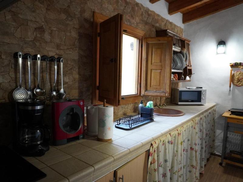 Rustikale Küche mit offenem Fenster, Gewürzen, Mikrowelle und Küchentüchern unter der Arbeitsplatte.