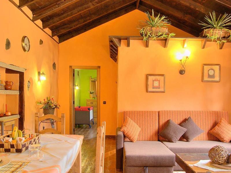 Gemütliches Wohnzimmer mit orangen Wänden, Holzdecke, Sofa und Dekorationen an der Wand.