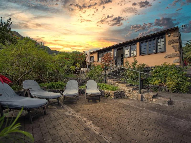 Terrazza accogliente con sedie a sdraio davanti a una casa al tramonto in un paesaggio pittoresco.