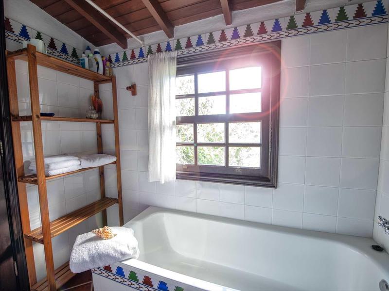 Bagno luminoso con vasca, finestra e scaffali con asciugamani.