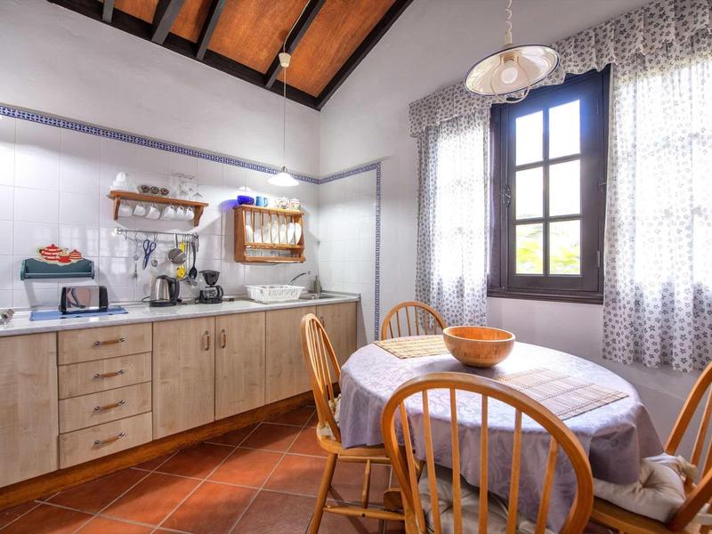 Sala da pranzo luminosa con mobili in legno, tavolo rotondo e soffitto decorativo.