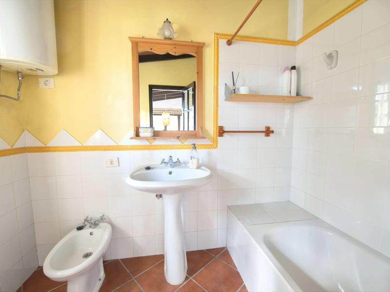 Bagno luminoso con lavabo, bidet, vasca da bagno e piastrelle giallo-bianco.