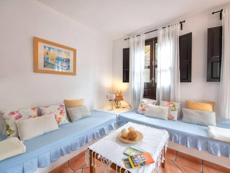 Zona salotto accogliente con cuscini blu, cuscini e un tavolino in una stanza luminosa.