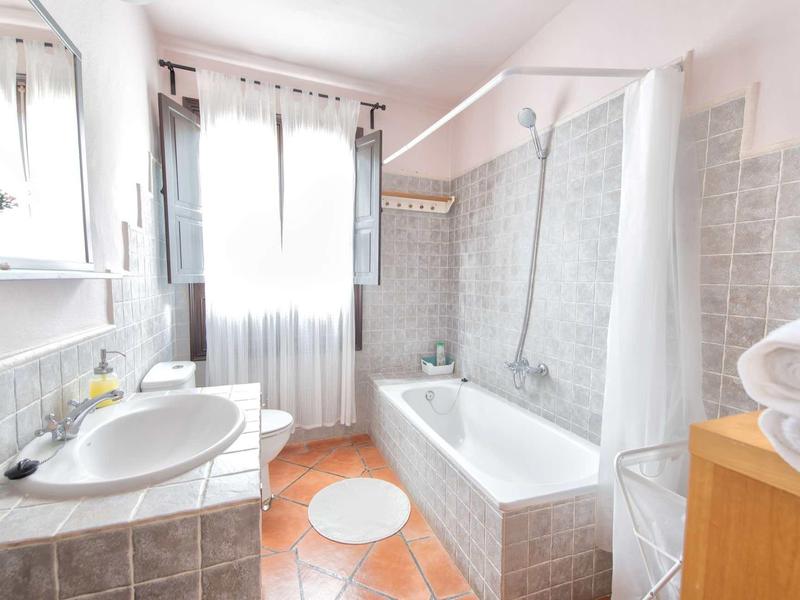 Bagno luminoso con vasca da bagno, lavabo, finestra e pareti piastrellate.