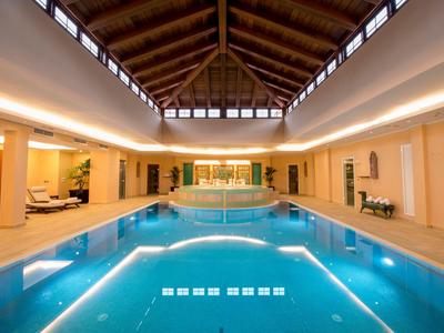 Elegant indoor pool with wooden ceiling and cozy seating areas in a hotel.