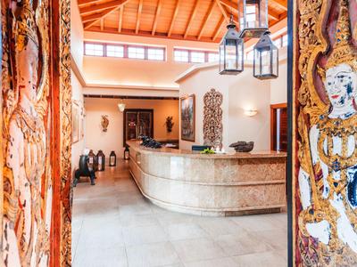 Entrance area with curved reception desk, wooden ceiling, and decorative doors.
