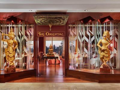 Eingang zu einem Restaurant mit zwei großen goldfarbenen Statuen und traditioneller asiatischer Dekoration.