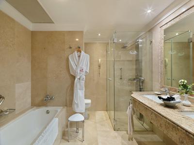 Helles Badezimmer mit Badewanne, Glass-Dusche, großem Spiegel und Marmor-Waschtisch.