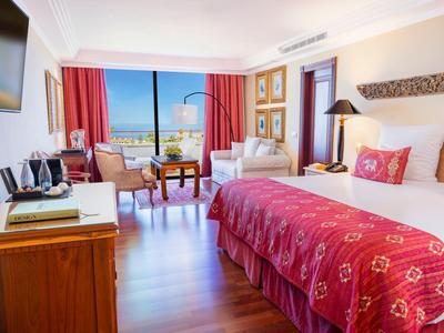 Chambre d'hôtel lumineuse avec grand lit et vue sur la mer à travers les fenêtres