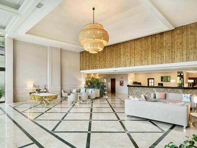 Elegante Hotellobby mit modernen Möbeln, großen Fenstern und Marmorboden.