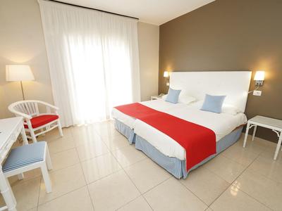 Modernes Hotelzimmer mit Doppelbett, weißen Möbeln und rotem Dekor.