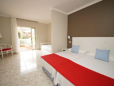 Helles Hotelzimmer mit Doppelbett, weißer und roter Bettwäsche, Zugang zu Balkon oder Terrasse.