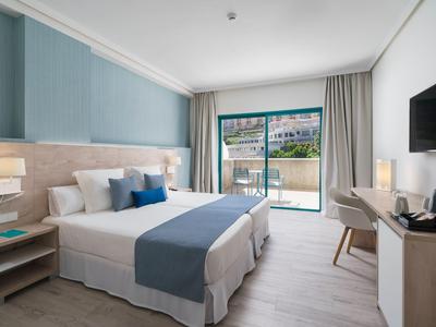 Camera d'hotel moderna con letto matrimoniale, zona salotto e balcone con vista piscina