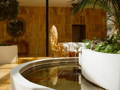 Moderní odpočinková zóna s kulatou vodní nádrží a rostlinami v světlém prostředí.