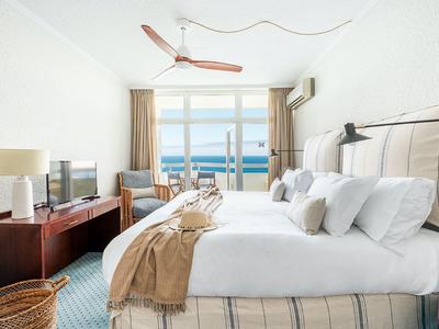 Pohodlný hotelový pokoj s manželskou postelí, výhledem na moře a moderním dekorem.