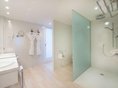 Salle de bain moderne avec douche en verre, serviettes blanches et design minimaliste.