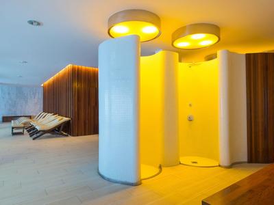 Espace spa moderne avec douches rondes et chaises longues sous une lumière chaude.