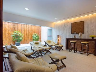 Coin salon confortable avec fauteuils, canapé et bar dans une pièce lumineuse.