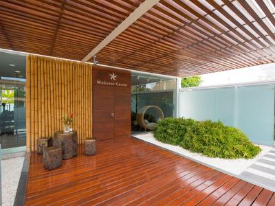 Espace jardin moderne avec terrasse en bois, végétation et entrée d'hôtel