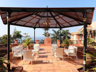 Kiosque ouvert avec des chaises et des tables blanches sur une terrasse avec vue sur la mer