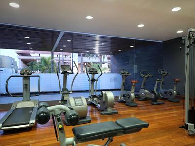 Salle de sport moderne avec tapis roulants, vélos et machines de musculation sur sol en bois.