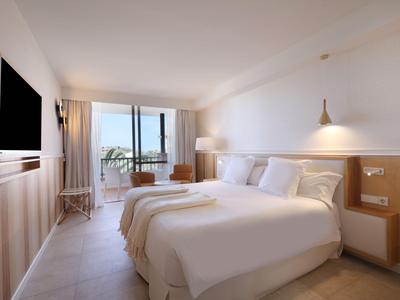 Chambre d'hôtel lumineuse avec lit double et balcon avec vue sur la mer.