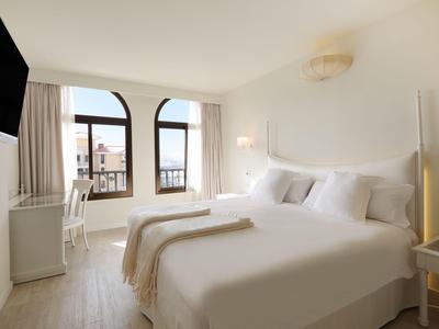 Chambre d'hôtel moderne avec deux lits simples, grande fenêtre et murs clairs.