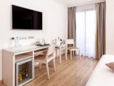 Nowoczesne miejsce do pracy w pokoju hotelowym z biurkiem, krzesłami i telewizorem na ścianie.