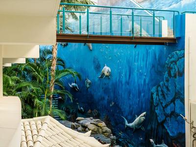 Pared del hotel con mural 3D realista de vida marina cerca de la piscina.