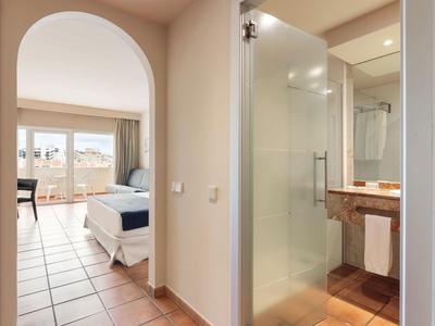 View through a hallway into a bedroom with a double bed and balcony access.