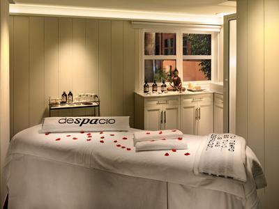 Accogliente stanza benessere con lettino da massaggio e petali di rosa decorativi.