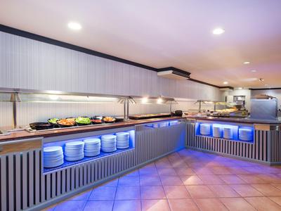 Strefa bufetu z oświetleniem, ladami i talerzami w restauracji hotelowej.