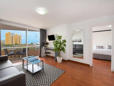 Nowoczesny salon z kanapą, dywanem, balkonem i widokiem na panoramę miasta w świetle dziennym.