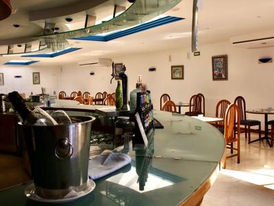 Innenansicht einer hellen Cafeteria mit gepflegten Tischen und Stühlen sowie einem großen Tresen.