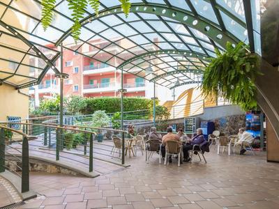 Espace extérieur couvert d'un hôtel avec sièges et plantes dans une station de vacances.
