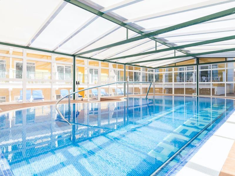 Piscina interna riscaldata con tetto in vetro e luce naturale in un hotel.